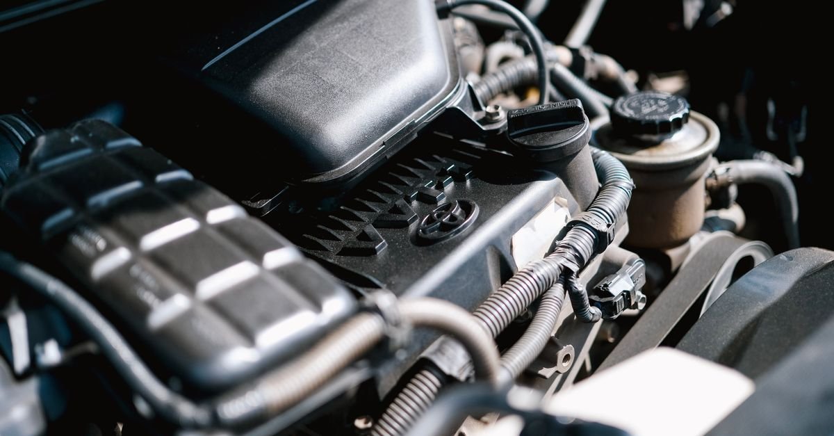 Close-up of engine bay wiring, cables and electrical connectors running between components under the hood