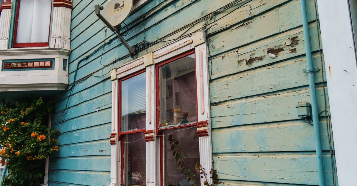 A rustic wooden house wall with sun-faded, powdery aged paint