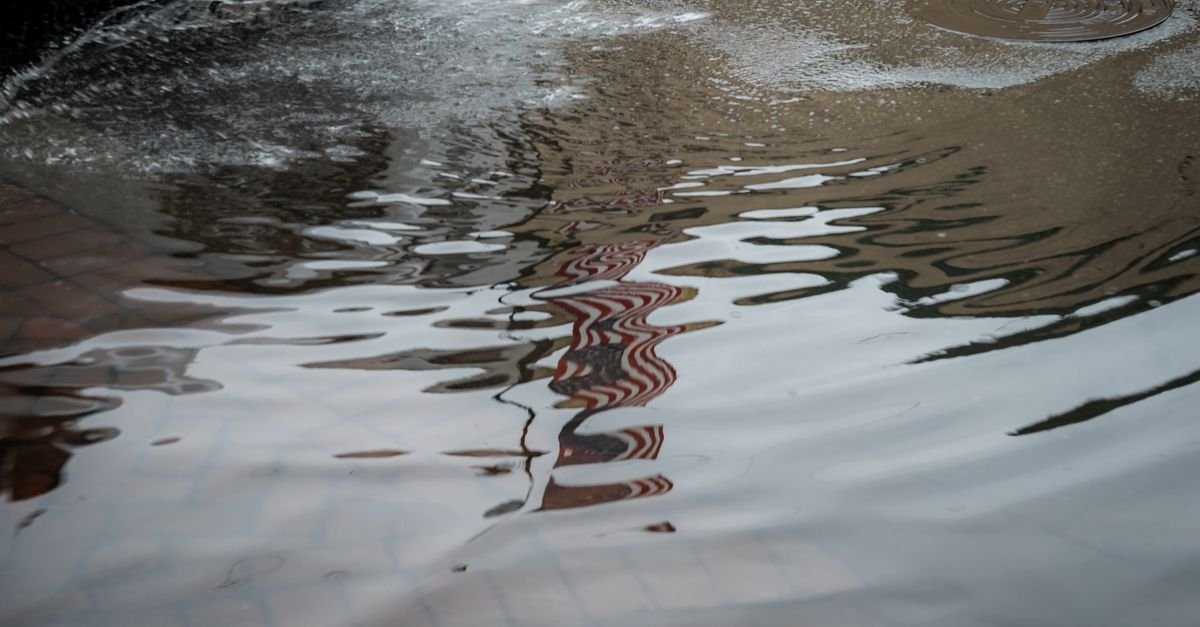 A residential street standing under floodwater after heavy rain, with no capacity left in the ground or the drains
