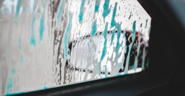 Turquoise soap foam clinging to a vertical pane of glass and slowly running down it