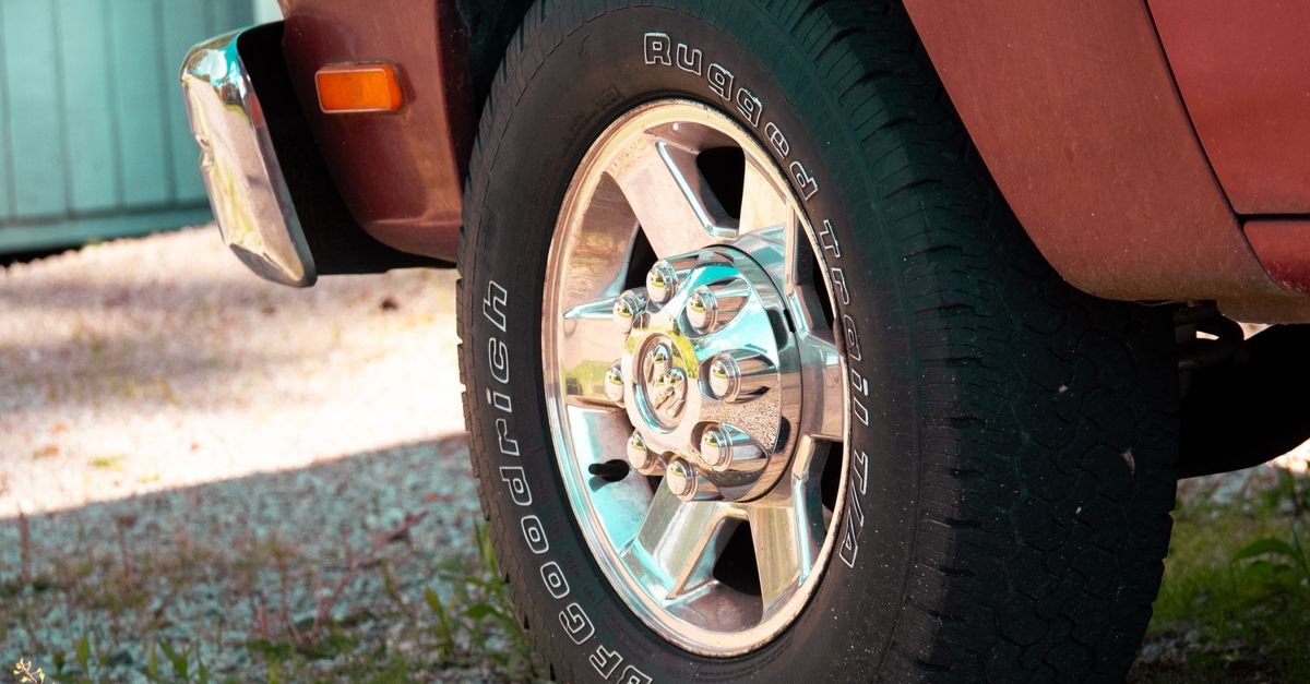 A polished chrome truck wheel and tyre on gravel
