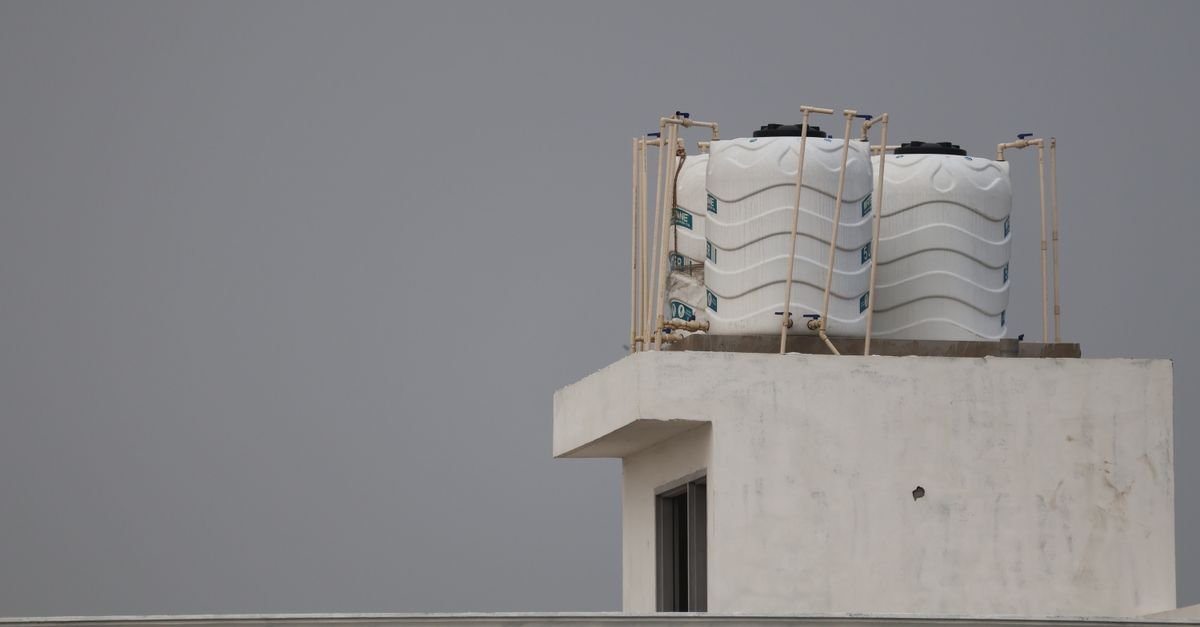 White poly water tanks raised on a rooftop, the elevation that gravity feed depends on