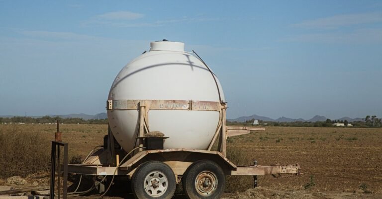 Round poly water tank mounted on a trailer in a rural field, the usual way water reaches a job with no tap
