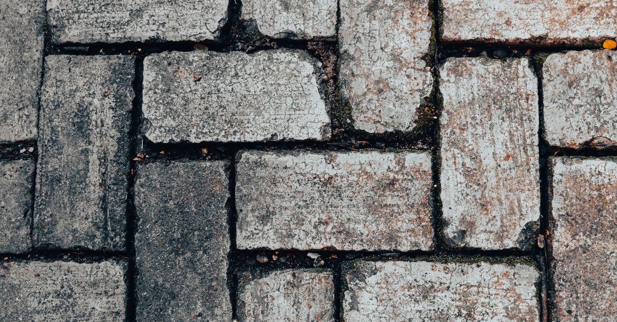 Close-up of grey stone paving blocks showing the open surface texture between and across the slabs