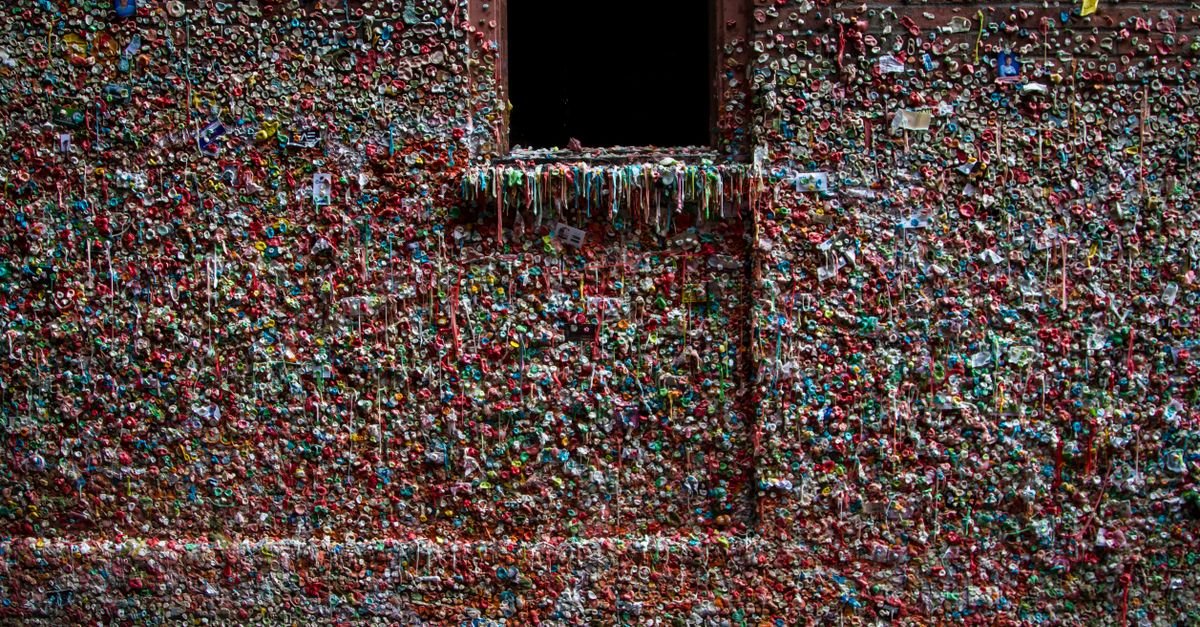 A wall in an alley completely covered in layers of multicoloured chewed gum