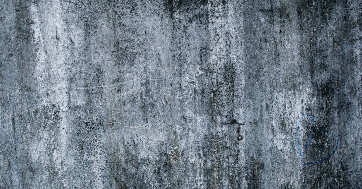 Rough grey concrete wall with a faint spray-painted heart still showing through after cleaning
