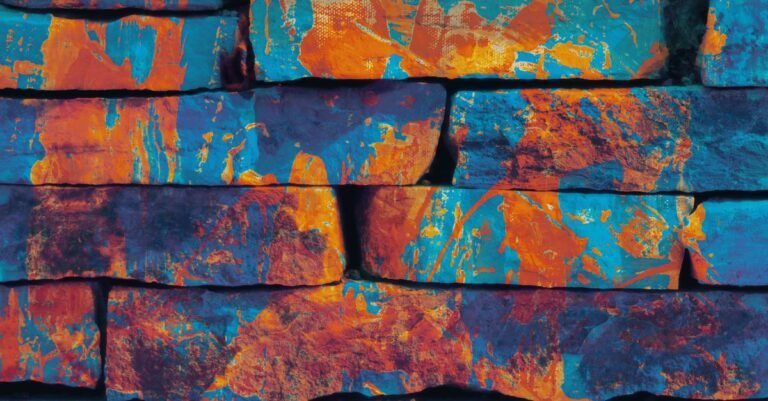 Orange and blue spray paint covering the faces and joints of a brick wall in close-up