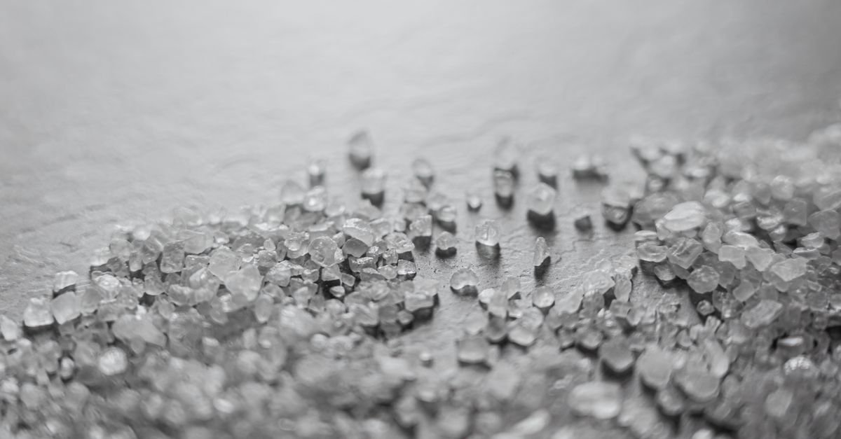 Macro shot of scattered coarse rock salt crystals showing their rough crystalline texture