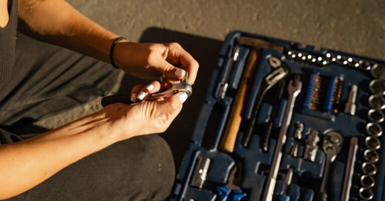 Hands lifting a spanner from an open tool roll on a workshop bench