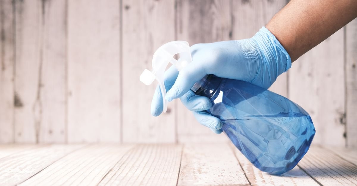 Gloved hand holding a spray bottle of cleaning concentrate before dilution
