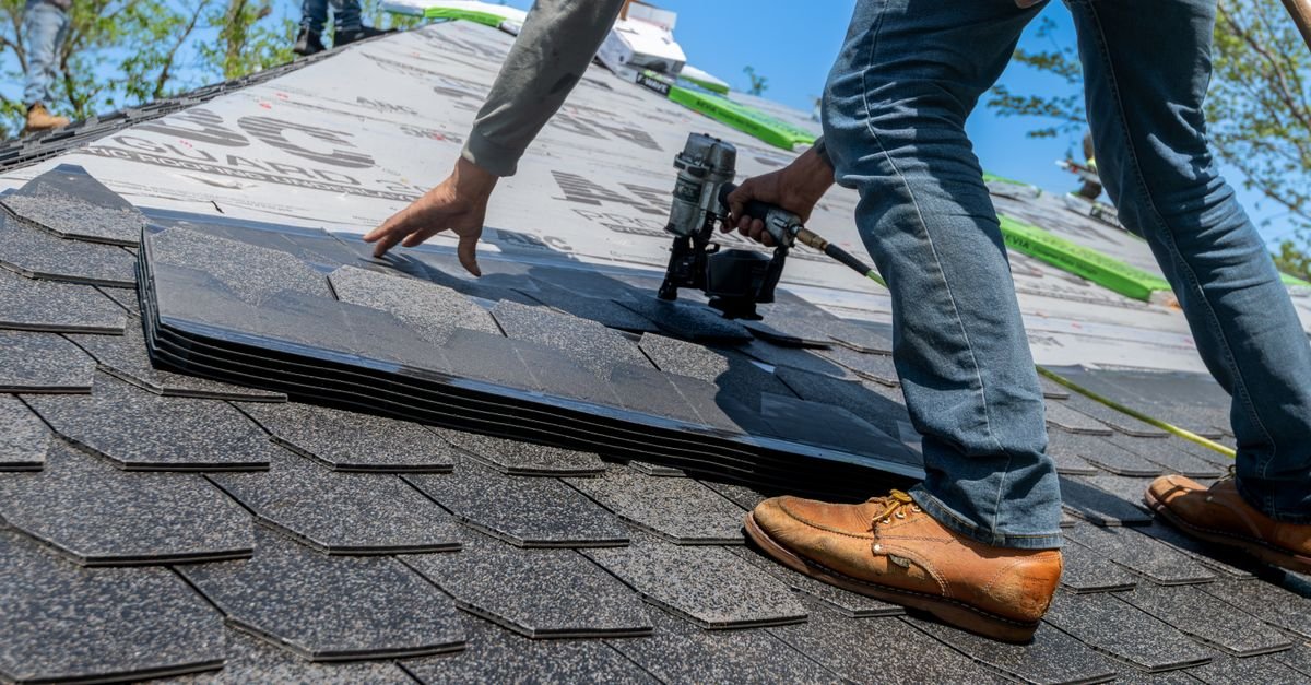 Roofer fitting new asphalt shingles, showing the fresh ceramic granule surface that soft washing is meant to preserve
