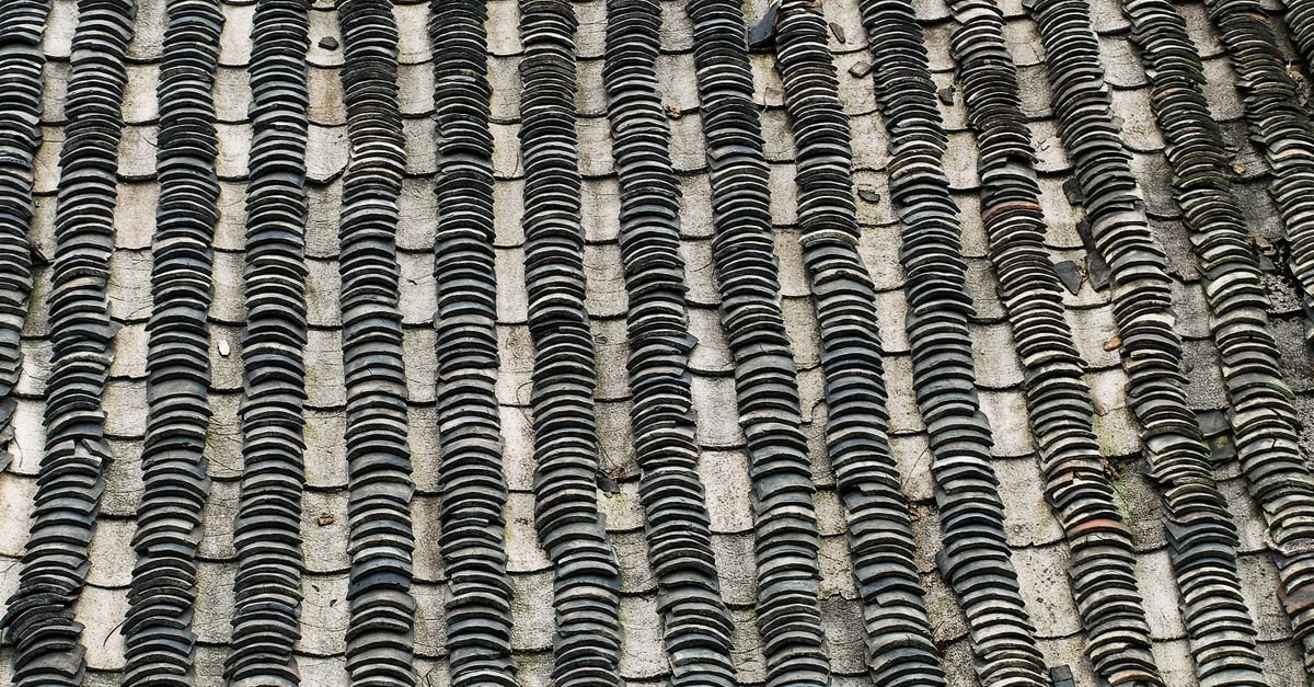 Traditional natural slate roof laid in overlapping courses, each slate cleft from metamorphic rock