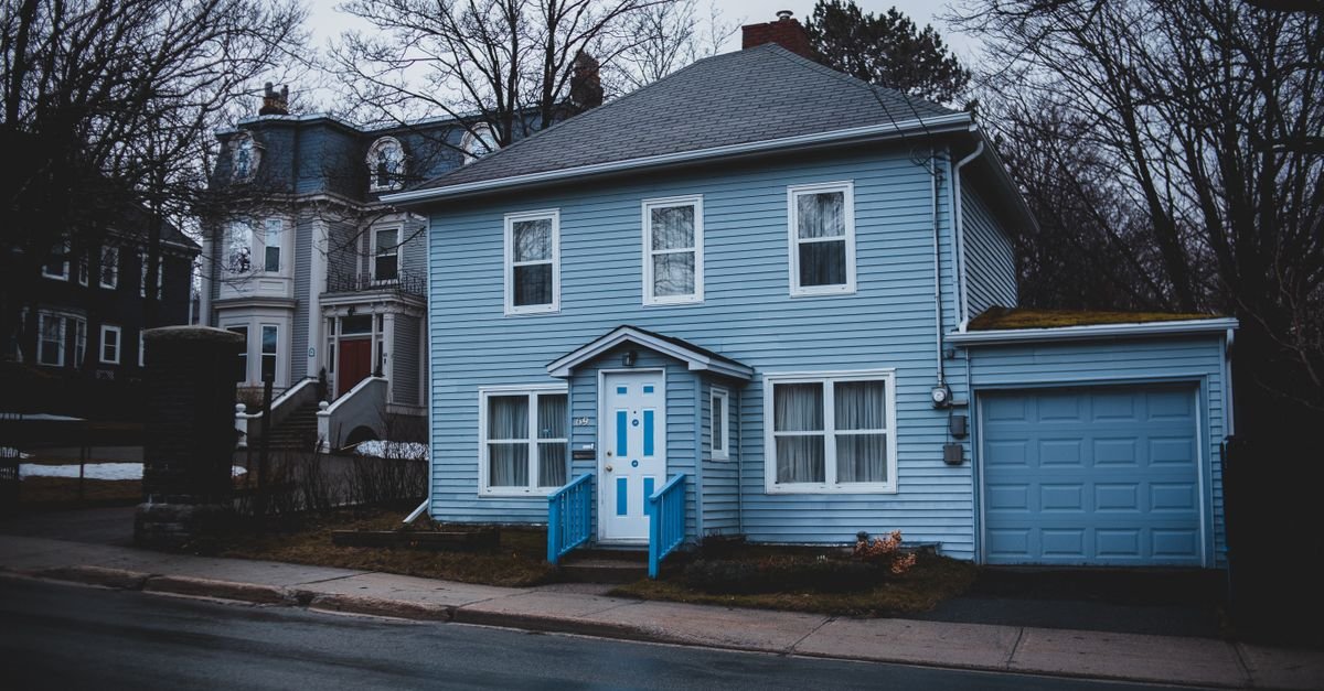 A small house clad in light blue horizontal wooden panels, showing the lapped courses and white trim