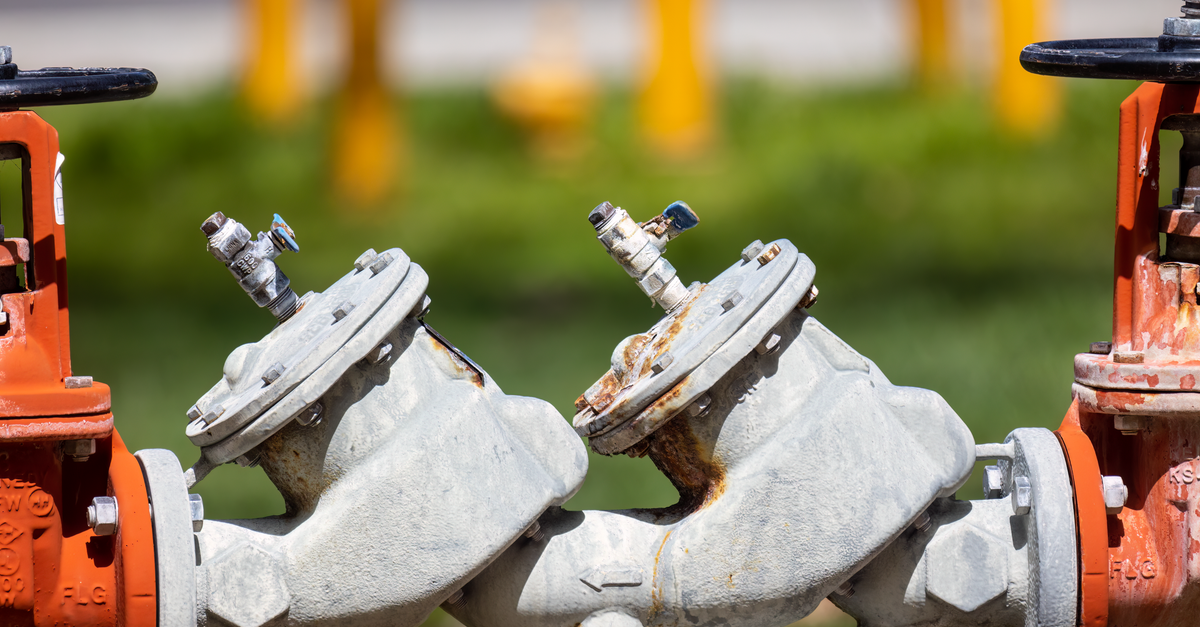 Rusted outdoor valves and fittings on an industrial gas line in sunlight