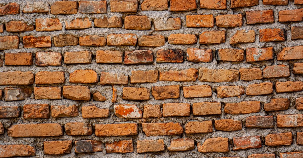 Close-up of an aged brick wall showing the open texture of the brick faces and the sand in the mortar joints