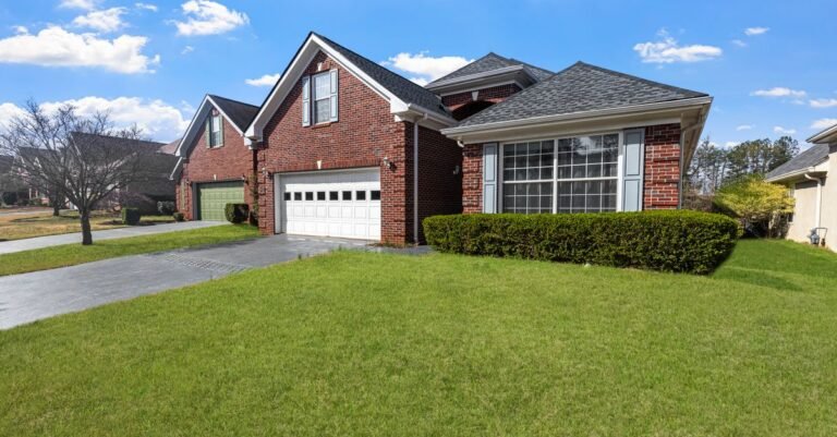 Red brick suburban house with a mown lawn, the kind of wall that gets soft washed rather than pressure washed