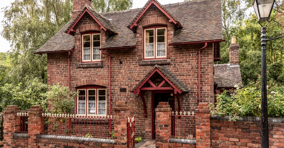 A traditional English brick cottage with climbing plants and a tiled roof, the kind of wall built with soft lime mortar