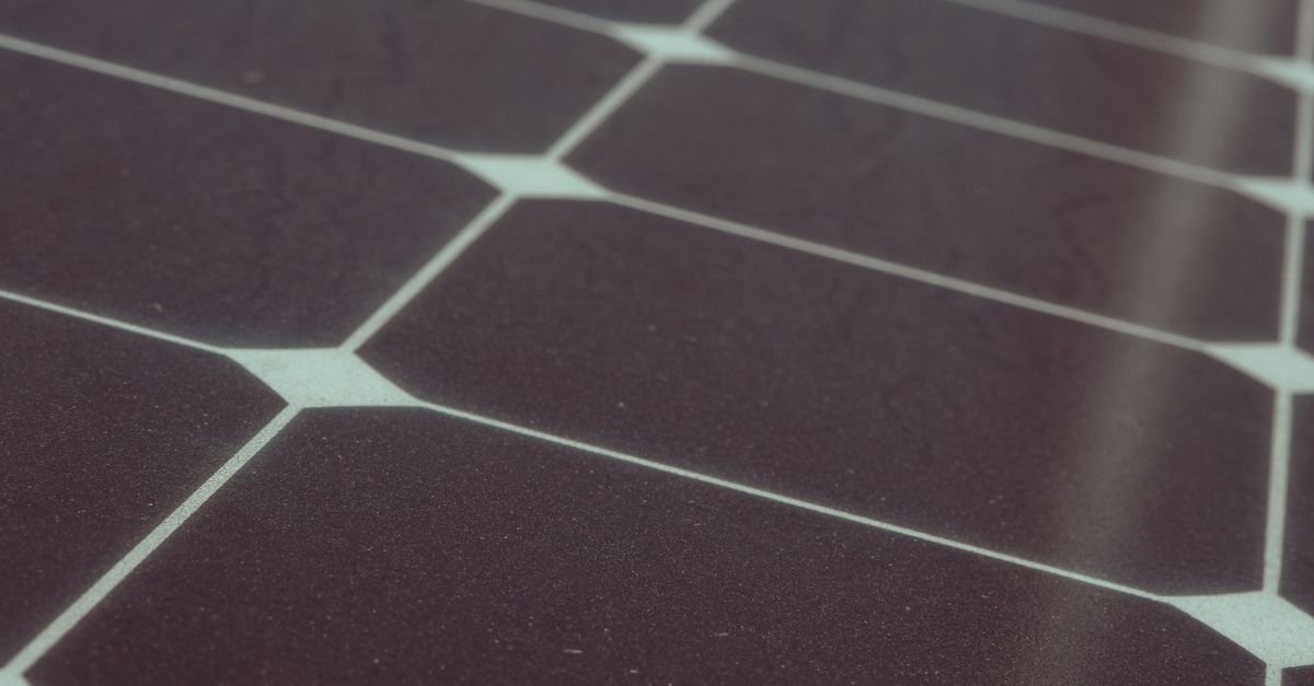 Close-up of solar cells inside a module showing the grid of fingers and the metal interconnect ribbons running between them