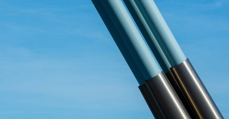 Slender steel tubes rising against a clear blue sky, the shape of a long extension held up towards a roofline