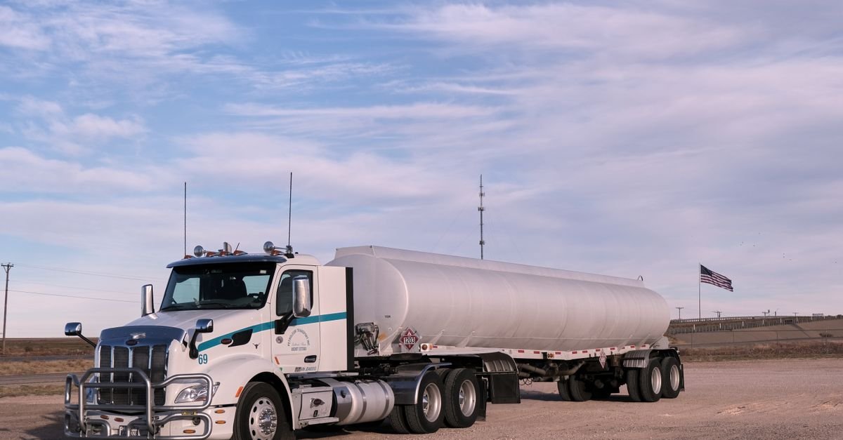 A polished aluminium fuel tanker parked outdoors, the bright metal an aggressive presoak will frost
