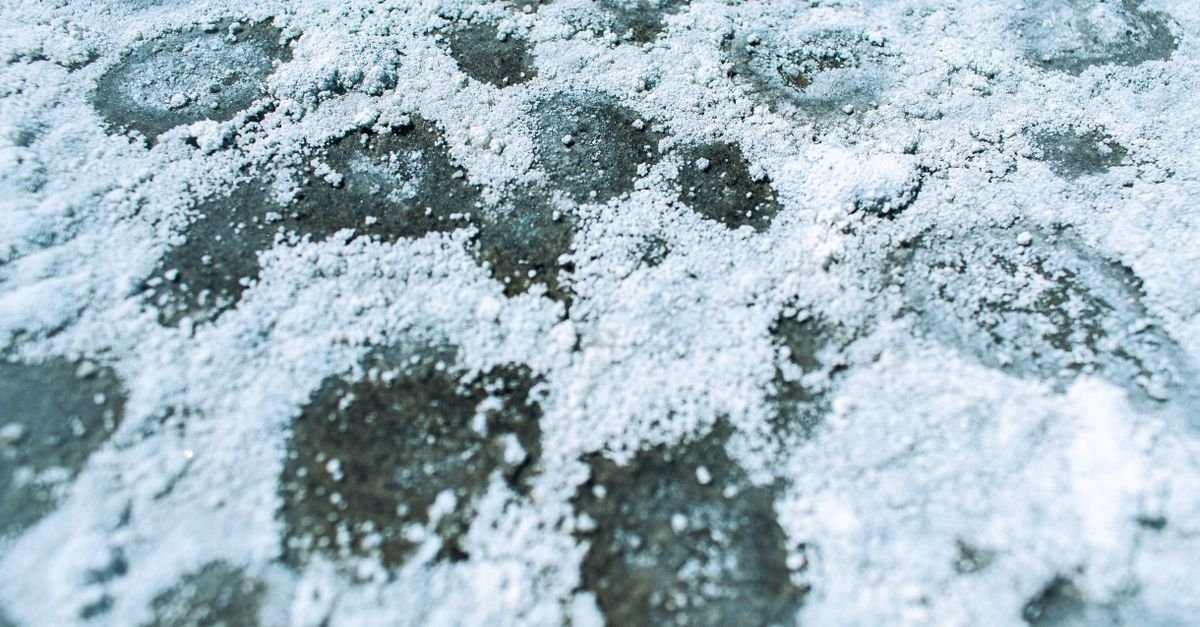 Close-up of white crystalline salt deposits forming a pattern across a flat surface