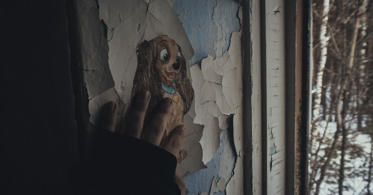 A hand pressed flat against an old painted wall where the coating has started to lift away