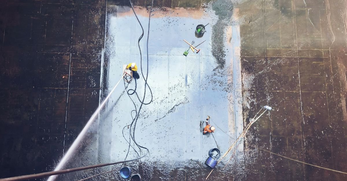 Overhead view of workers cleaning a large industrial floor with high water volume