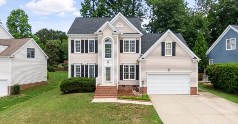Two-story suburban home with clean tan vinyl siding and a two-car garage