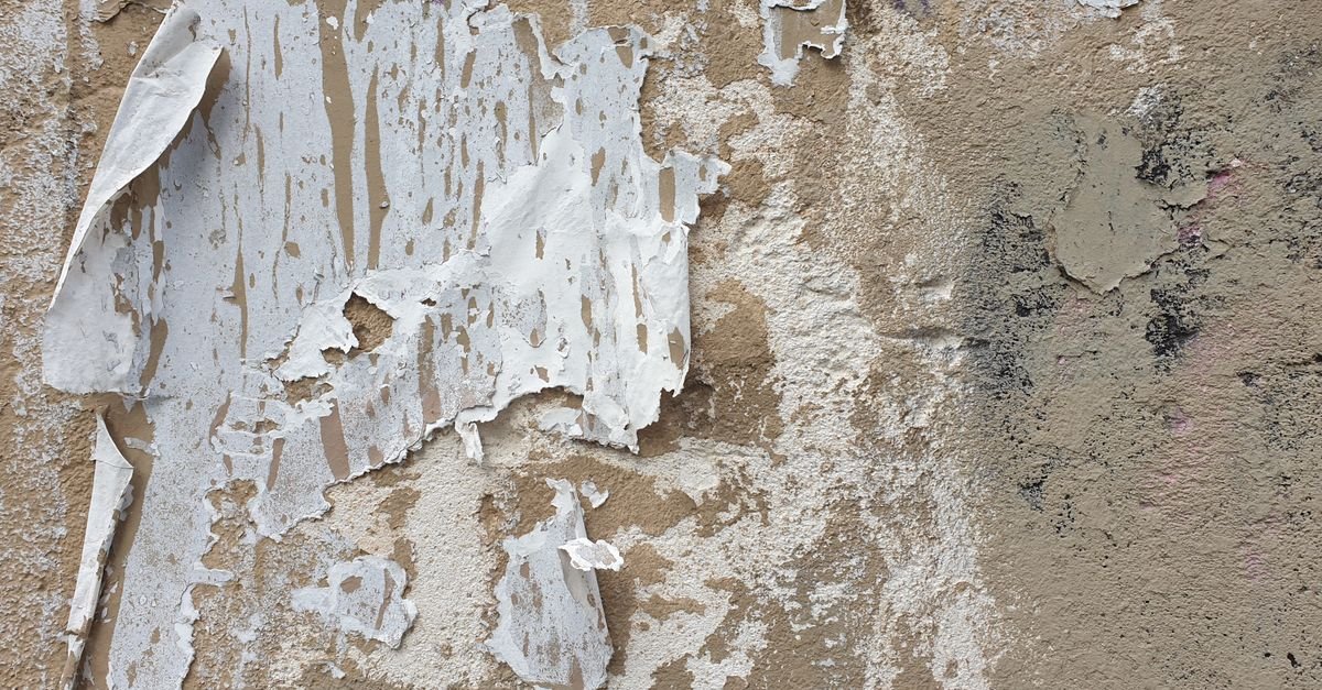 Heavily peeling paint over a stucco wall, a condition pressure washing makes worse