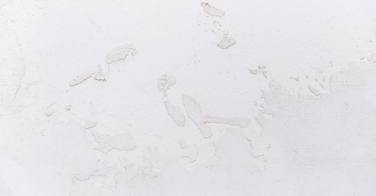 Close-up of cracked white stucco surface that should be repaired before any pressure washing