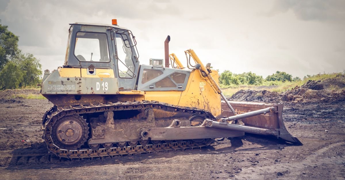 A bulldozer standing on churned, muddy construction ground, the kind of plant that is washed by volume rather than by force