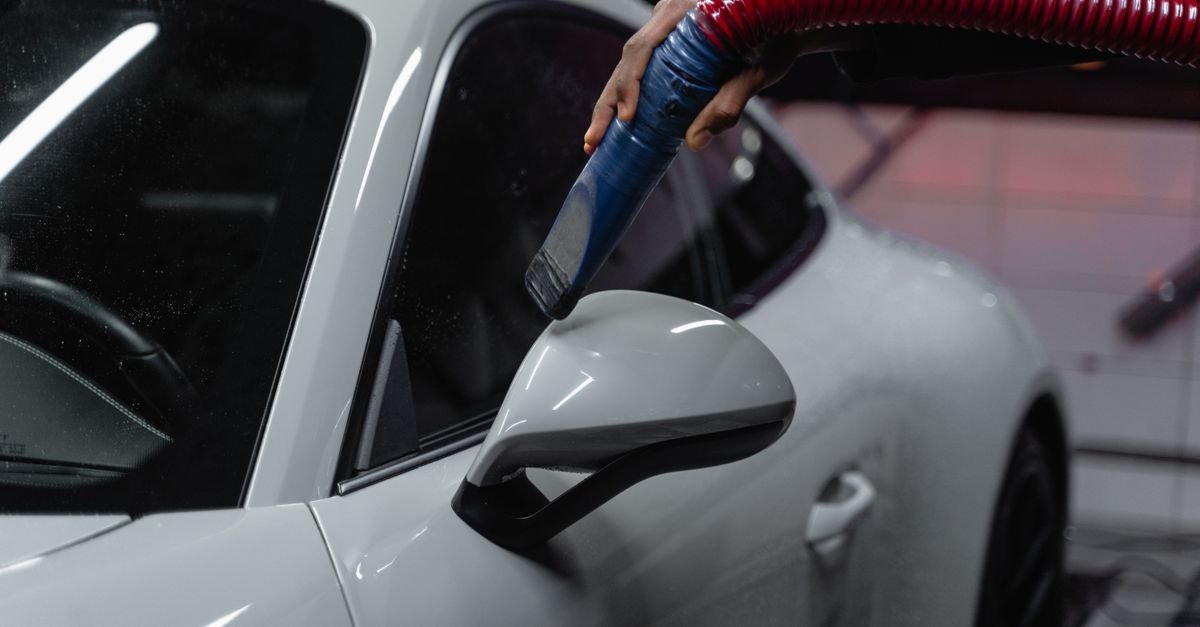 A white sports car being vacuumed indoors during a detailing job