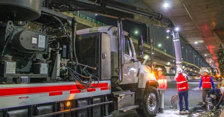 Municipal crew cleaning a street with machinery under an overpass at night, the kind of hours a commercial machine is bought for