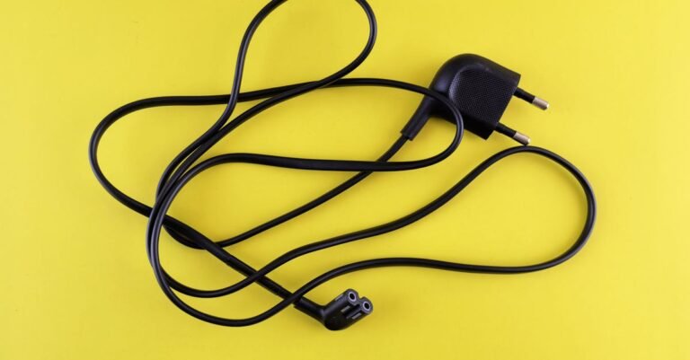 A tangled black power cord photographed against a bright yellow background