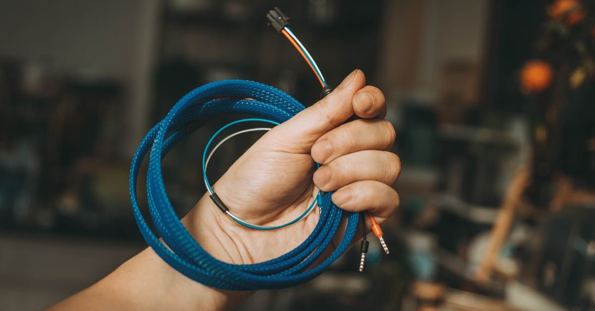 A hand holding a coiled length of cable, the last check before anything gets plugged in