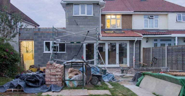 A suburban two-storey house mid-renovation with access equipment and building materials around it