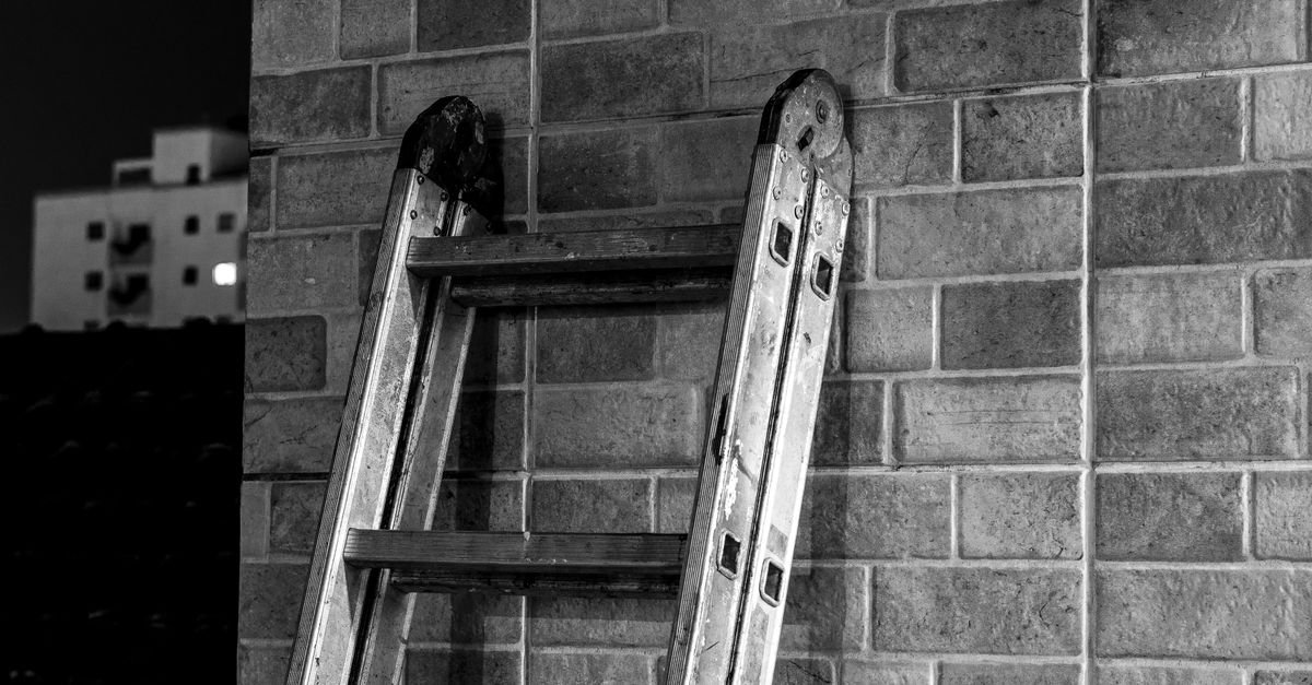 A metal extension ladder leaning against a brick wall, set at a working angle