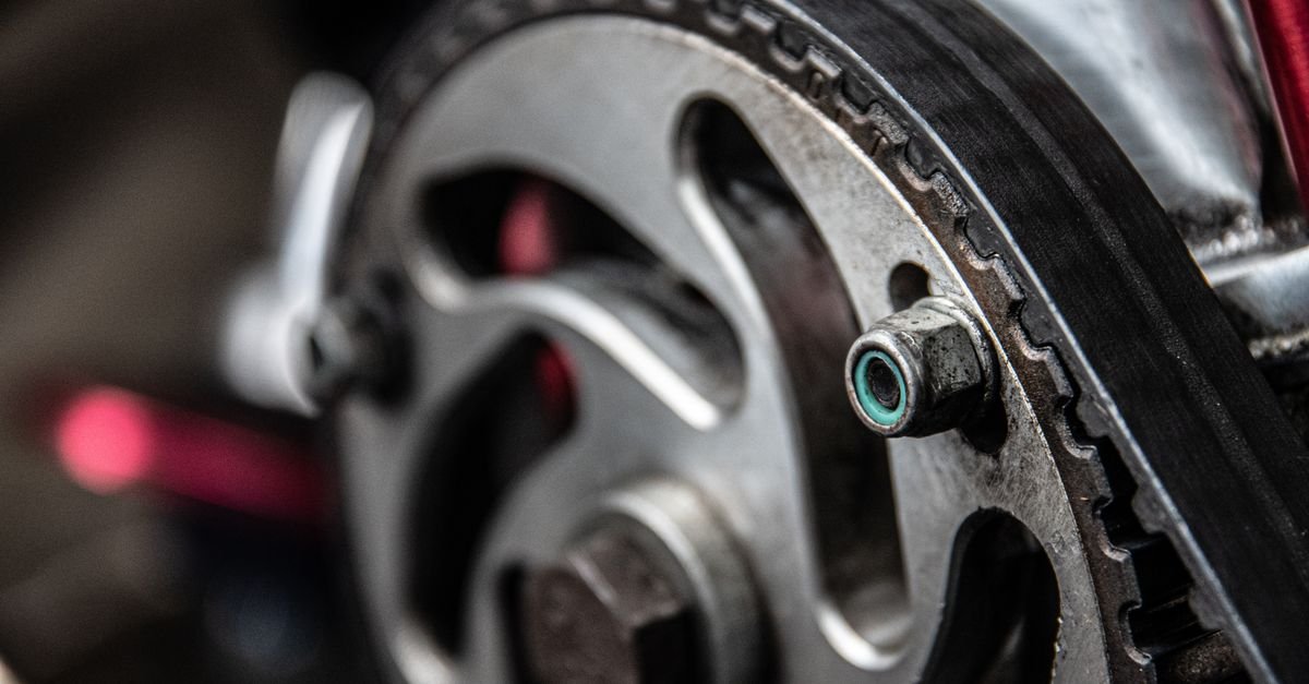 Close-up of a toothed drive belt wrapped around a metal sprocket, the arrangement that lets a driven shaft turn slower than its engine