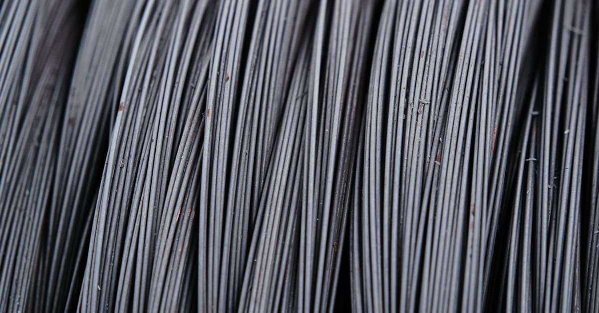 Macro view of intertwined steel wires showing the fixed braid angle that sets how tightly a high-pressure hose can be folded