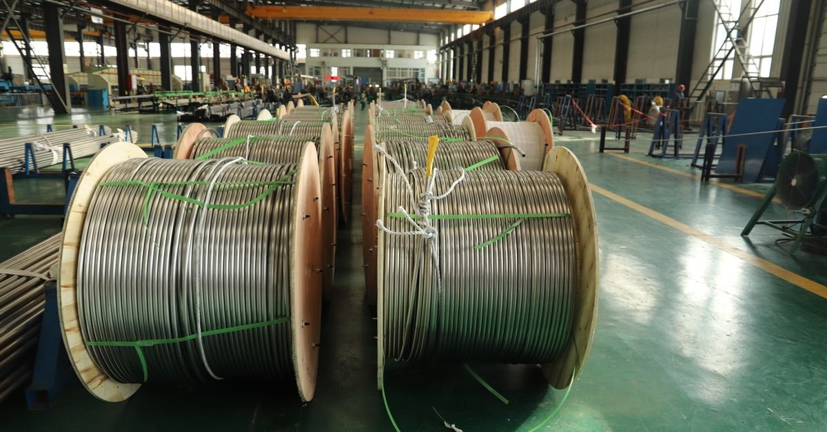 Rows of large steel cable reels of several drum diameters standing in an industrial facility