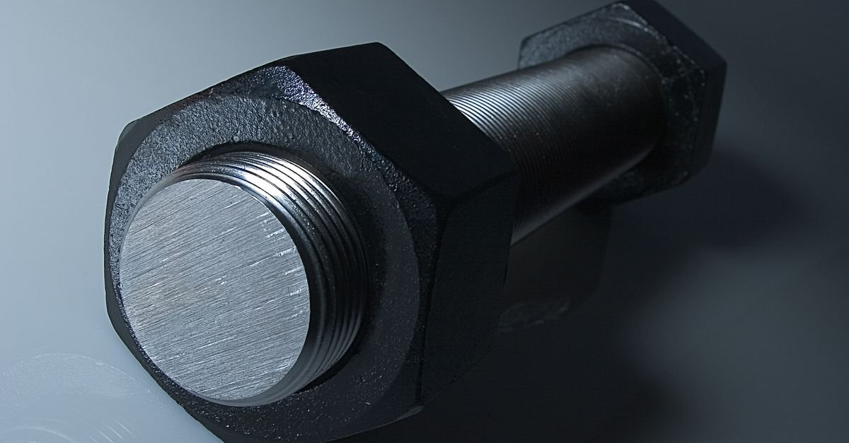 A large steel bolt photographed close up, the kind that holds a pump's mounting flange to an engine face