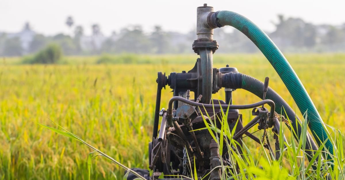 An engine-driven agricultural water pump running in a green field, the pump family that soft wash systems are built from
