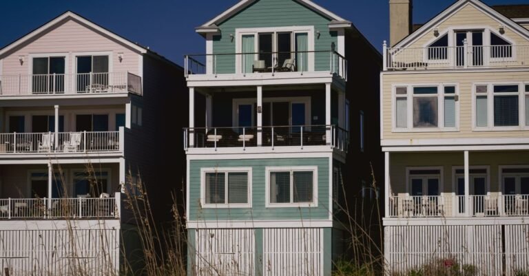 Colourful coastal houses clad in painted wooden siding, the kind of wall that is cleaned with chemistry rather than pressure