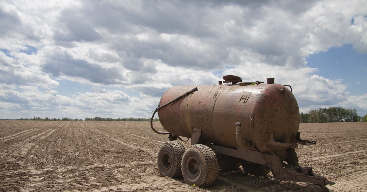 A towable water tank trailer standing in an open field, the delivery half of a soft wash system