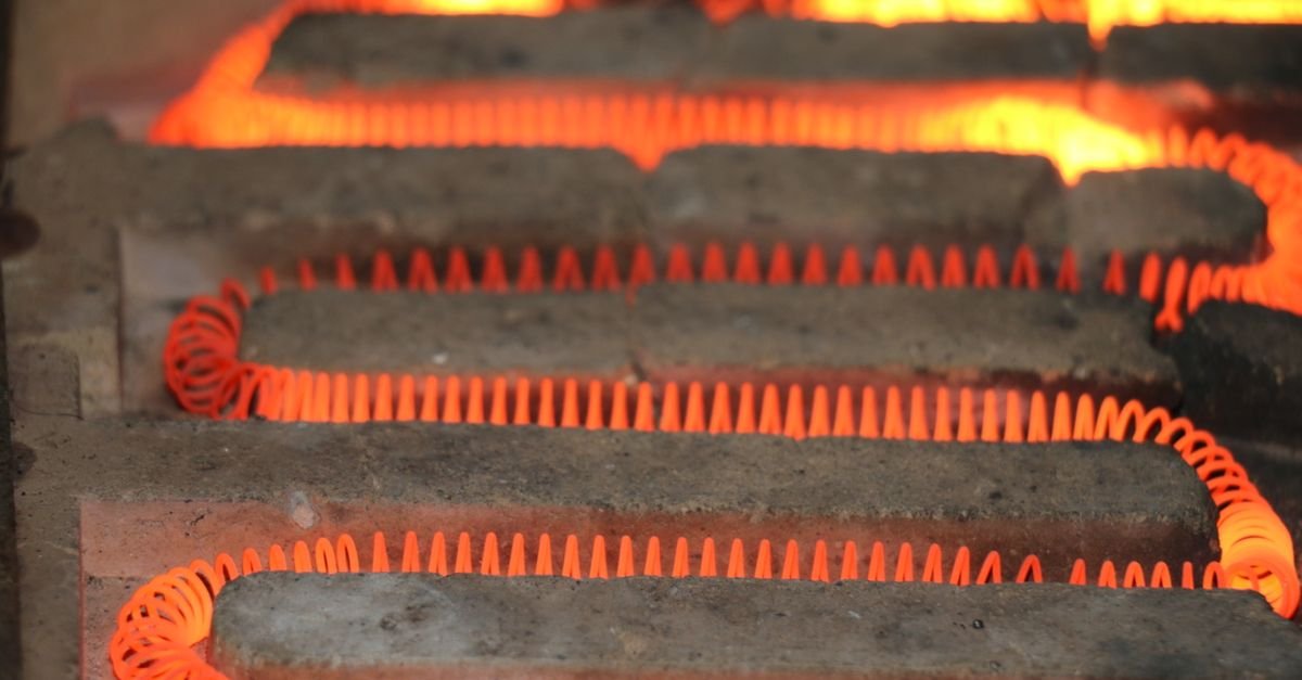 Close-up of a glowing coiled electric heating element, the component whose wattage sets the ceiling on how much steam a cleaner can make