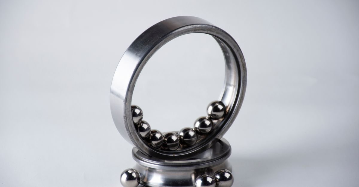 An arrangement of a stainless steel ball bearing with loose silver balls on a clean white surface