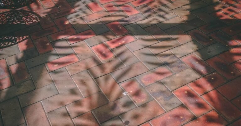 Alternating light and dark bands of shadow striping a red brick paved surface
