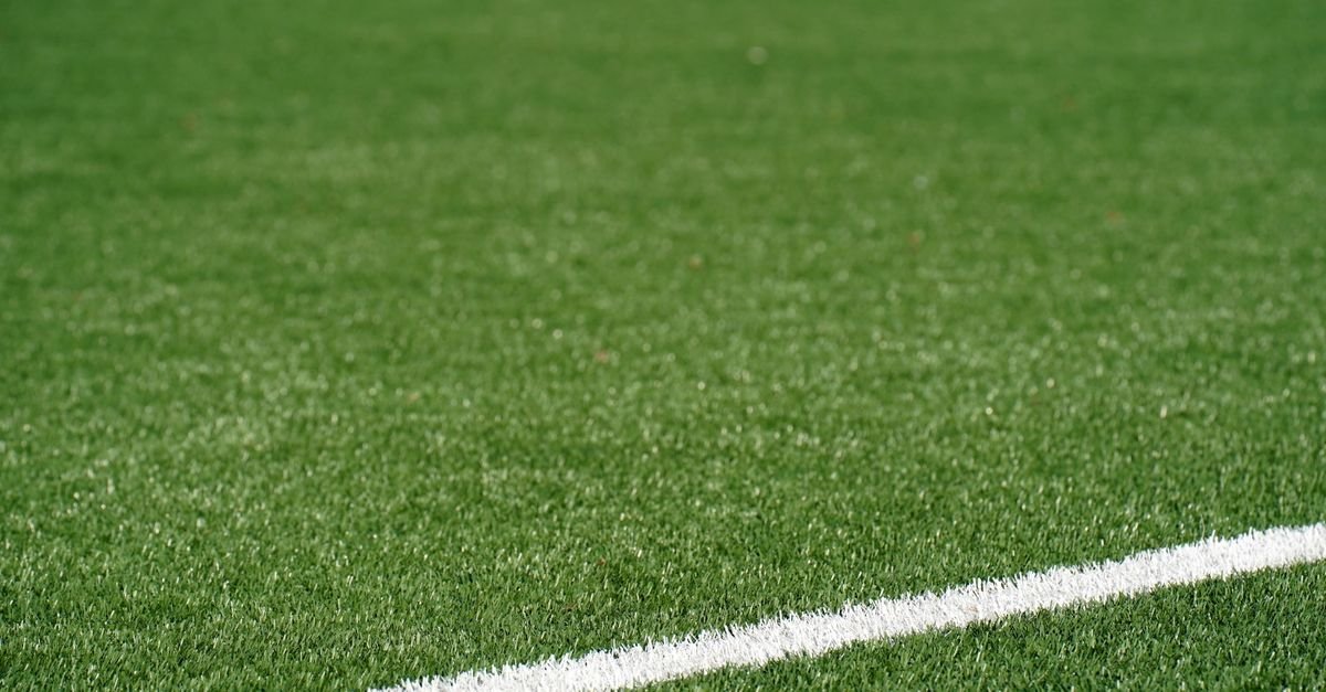 Close-up of green artificial turf with a painted white boundary line running across it